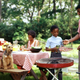 Family at picnic table beside a grill where they prepare to grill steaks